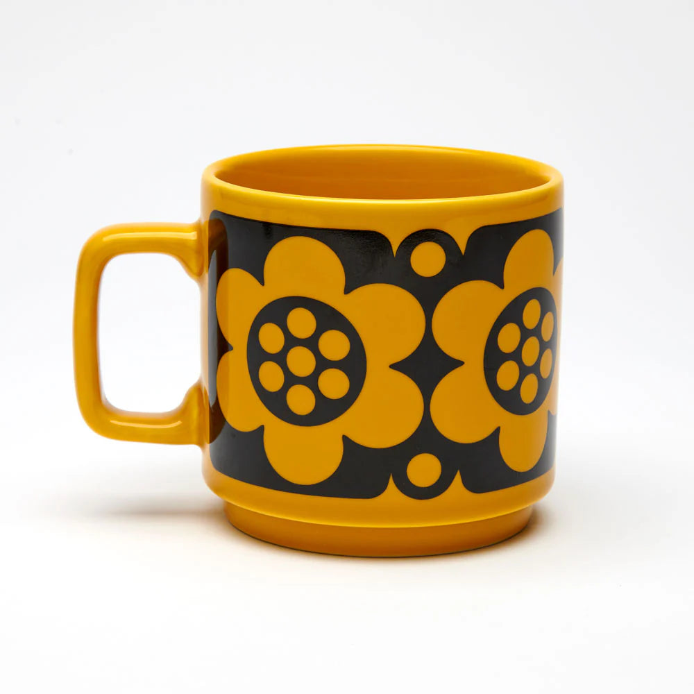 Yellow mug with black floral patterns on a white background