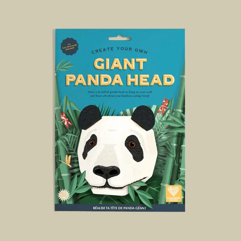 A product package for a craft kit titled 'Create Your Own Giant Panda Head' on a solid beige background. The package features a bright blue background with yellow text and an illustration of a panda head surrounded by green bamboo.