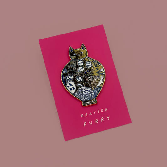 A decorative enamel pin of a cat shaped like a vase, mounted on a bright pink card. The pin features intricate white and gold details.