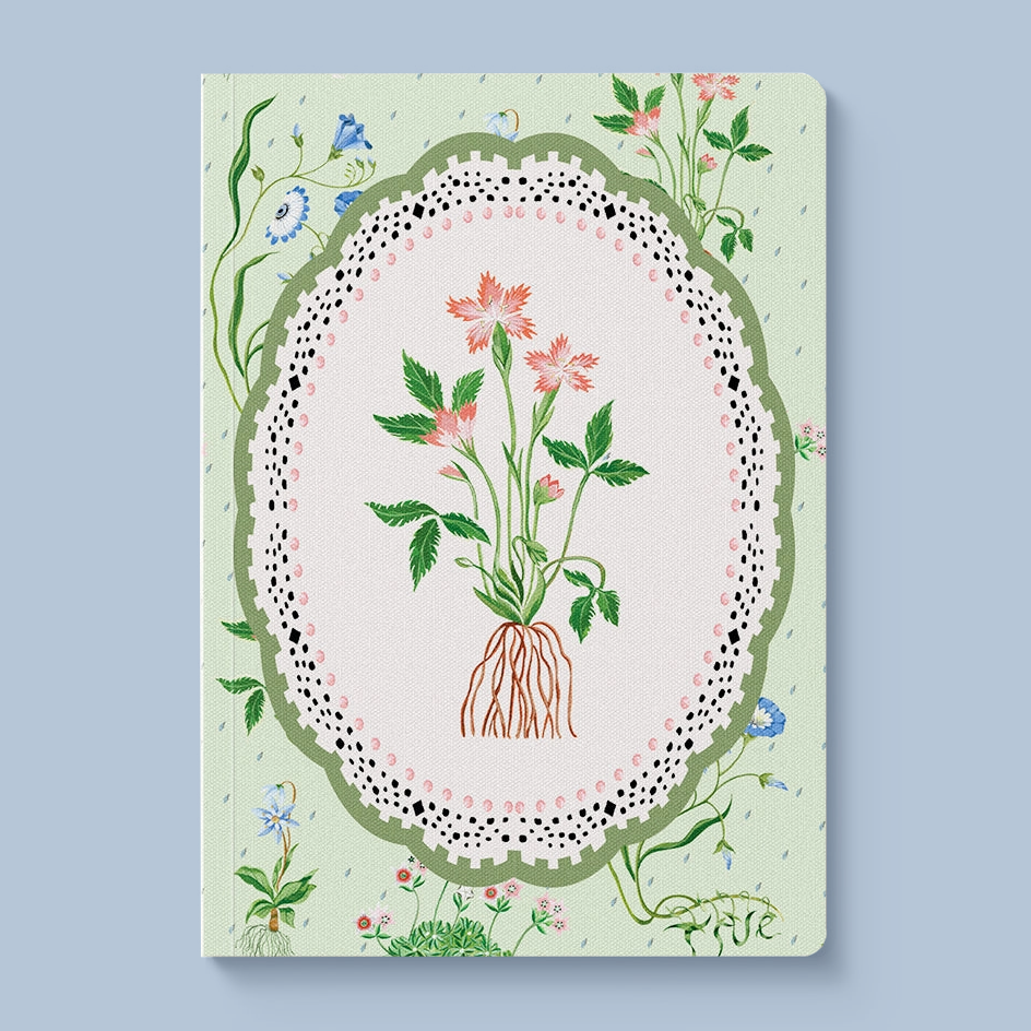 A hardcover notebook with a light green cover decorated with a central botanical illustration of pink flowers and green leaves inside an oval frame with a lace-like border, set against a solid light blue background.