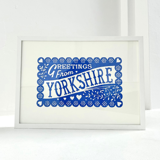 Framed print with 'Greetings from Yorkshire' text in blue on a white background