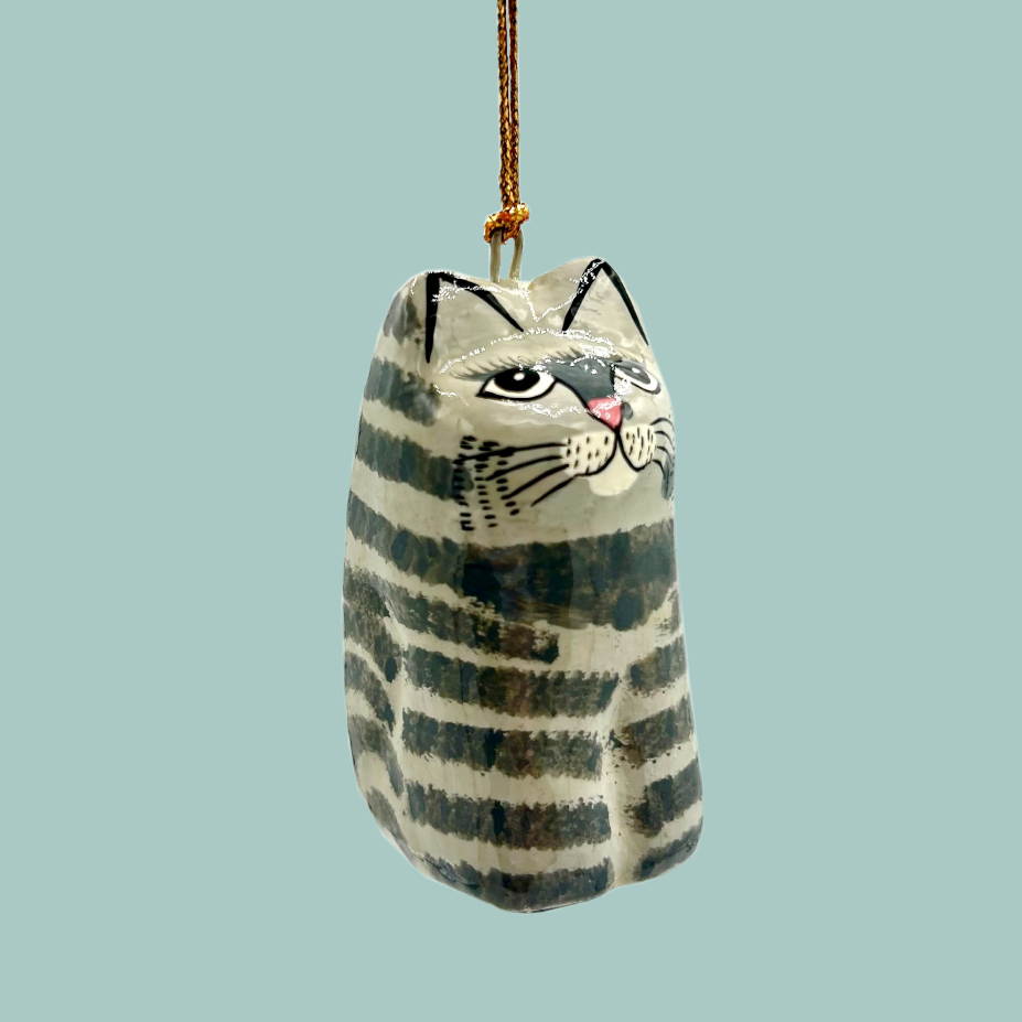 Cat-shaped ornament painted in grey stripes, hanging on a gold string. 