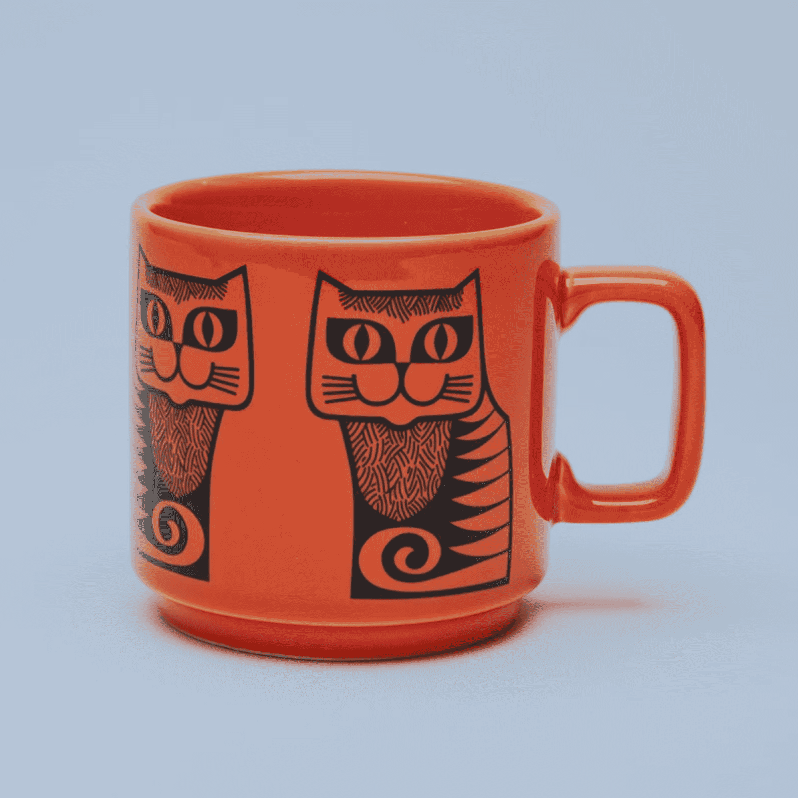 Orange mug with black cat illustrations on a light blue background