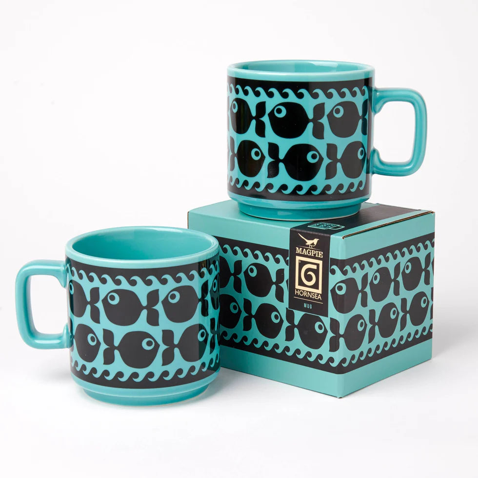 Two turquoise mugs with black fish pattern on a matching box against a white background