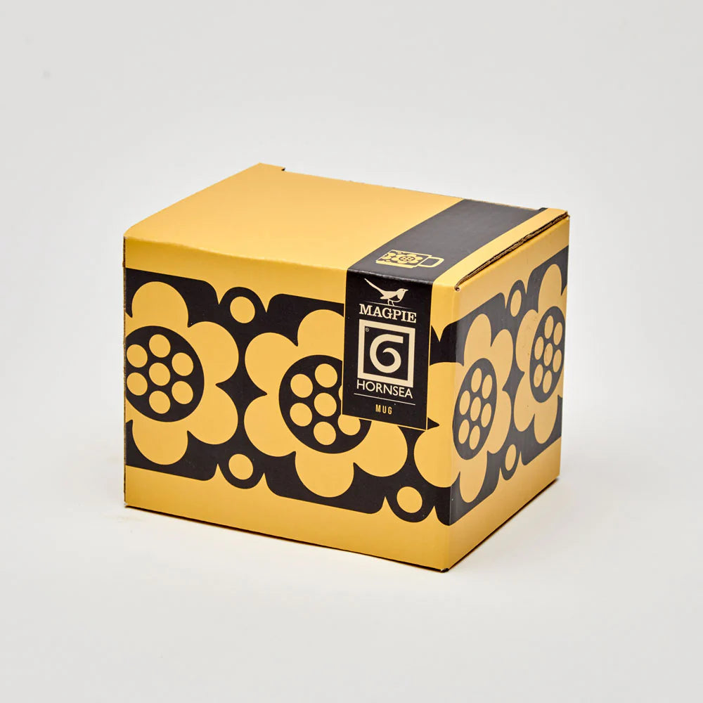 Yellow and black box with floral patterns and a brand logo on a light gray background