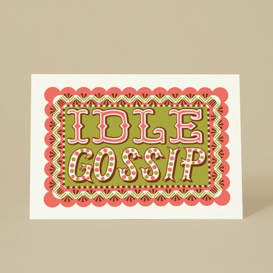A square greeting card with a retro-style graphic design featuring the words 'IDLE GOSSIP' in pink and white retro lettering on an olive green background, surrounded by a scalloped pink and green border. The card is displayed standing upright on a solid beige background.
