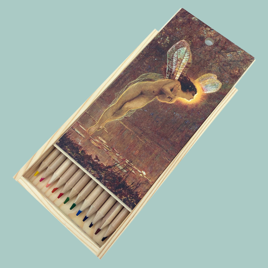 Set of colored pencils in a wooden box with fairy artwork on a light blue background