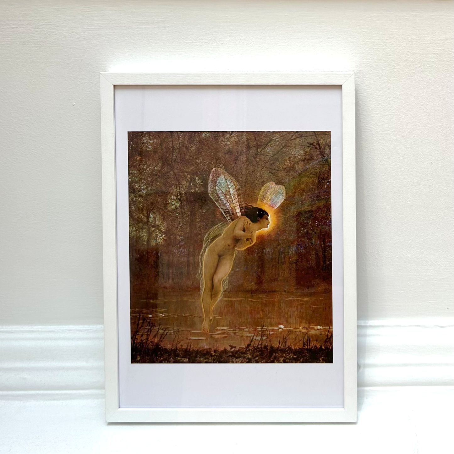 Framed artwork of a nude figure with wings in a forest setting