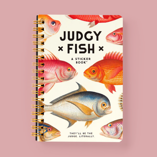 A spiral-bound sticker book titled 'JUDGY FISH' with colorful fish illustrations on the cover, photographed against a solid pink background.