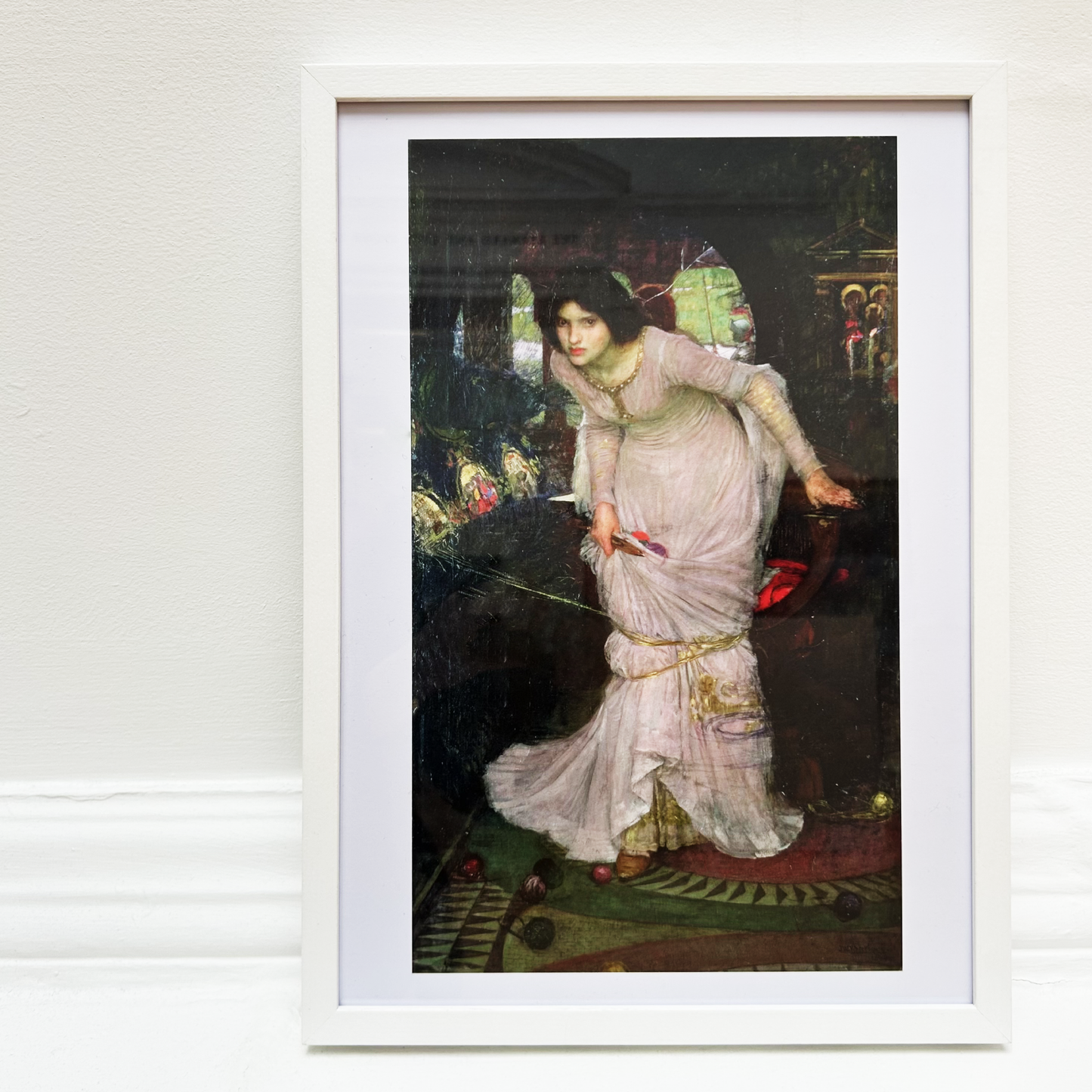 Framed painting of a woman in a white dress on a light gray wall.