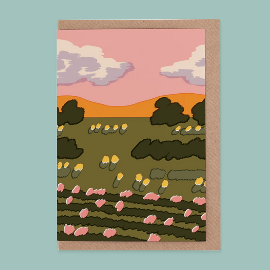 Greetings card of a landscape with trees, flowers, and a pink sky on a light blue background.