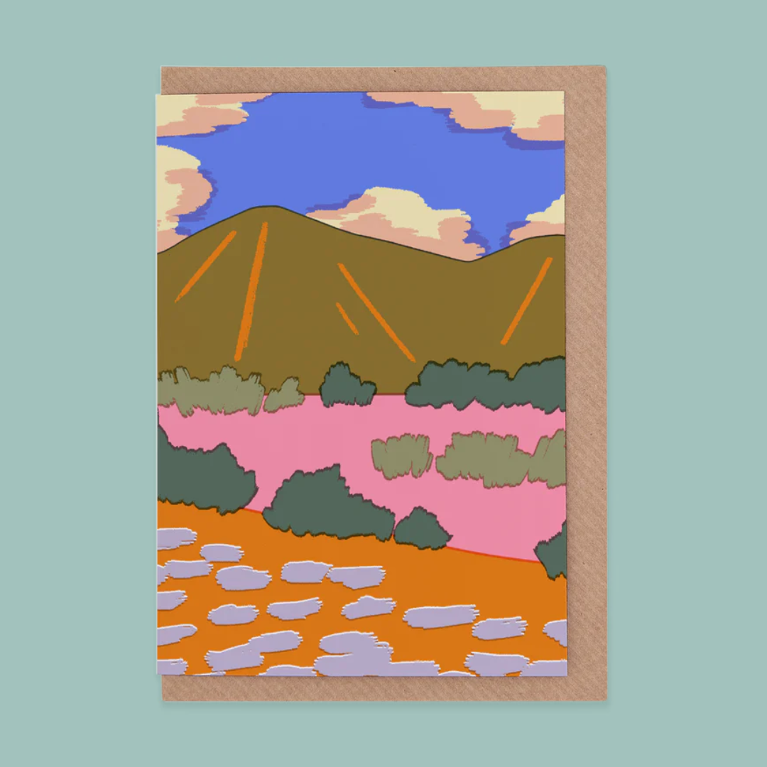 Greetings card of a landscape with mountains, trees, and water on a light blue background