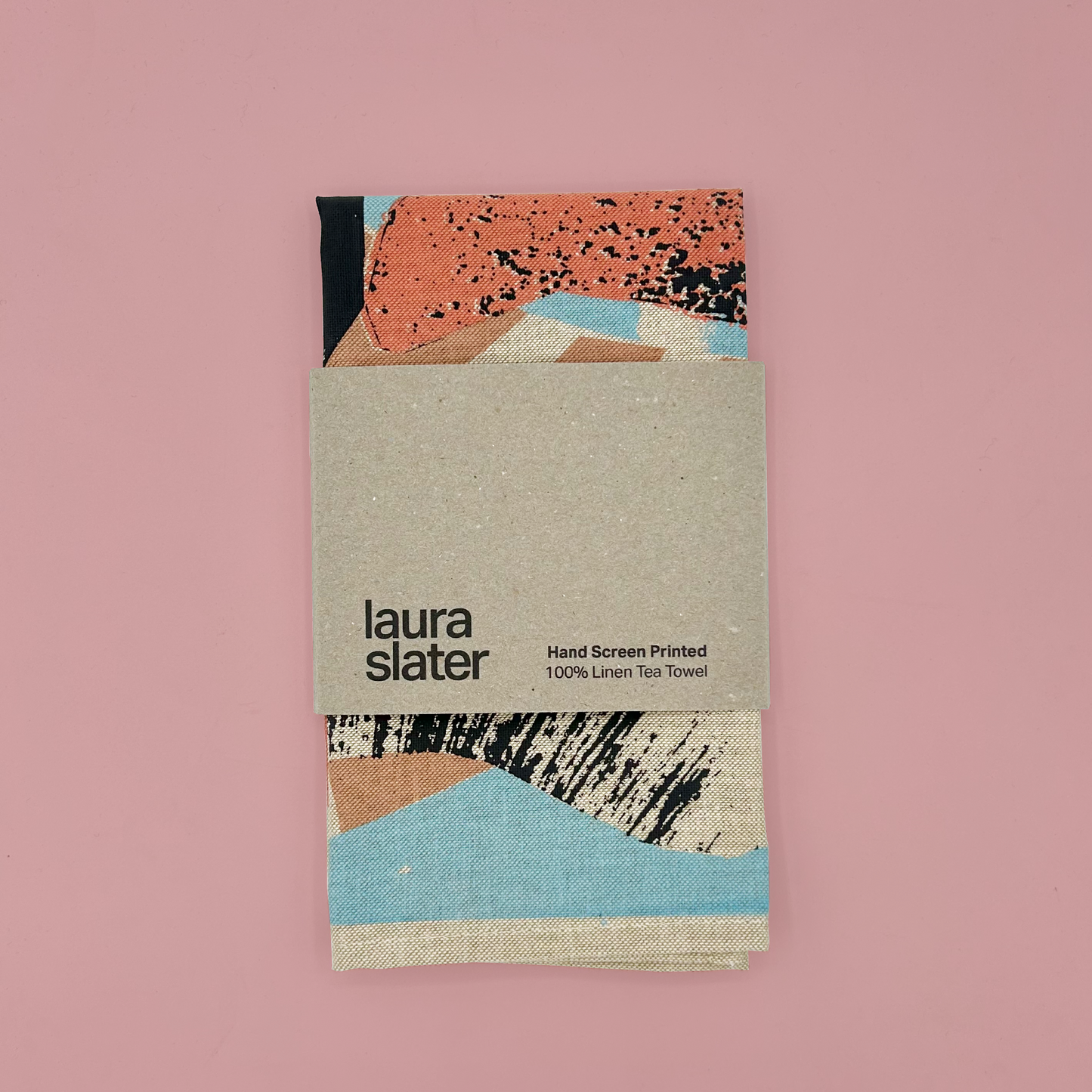 Tea towel with abstract design and 'laura slater' branding on a pink background