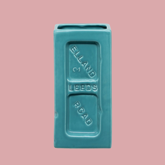 Turquoise rectangular ceramic vase with 'Elland & Leeds Road' text on a pink background
