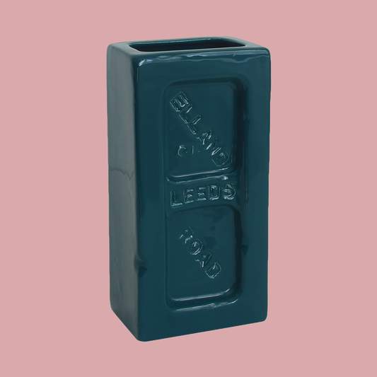 A teal ceramic brick-shaped vase with 'Leeds Elland Road' embossed on the side.