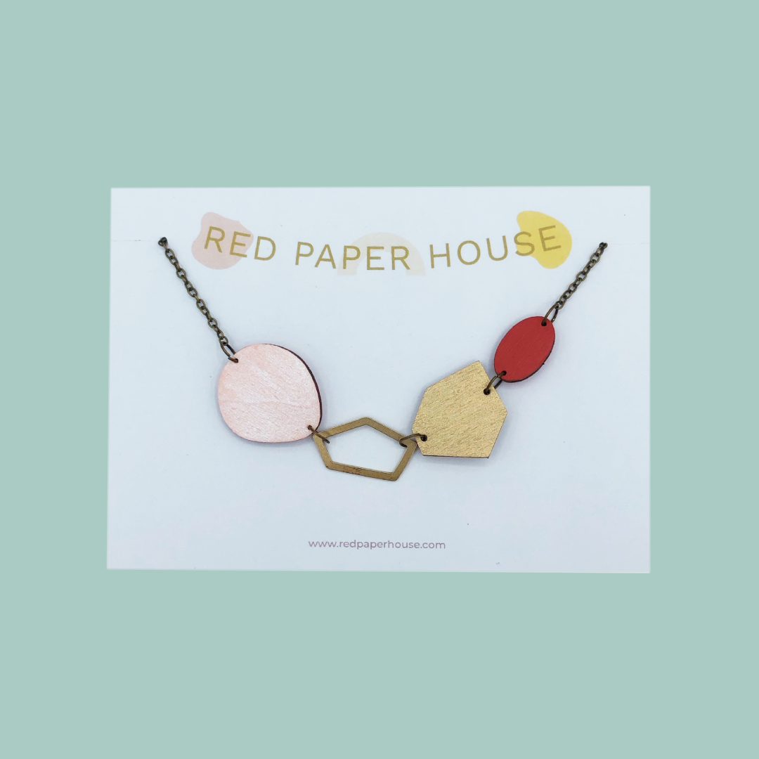 Geometric necklace on a card with 'Red Paper House' branding on a light green background