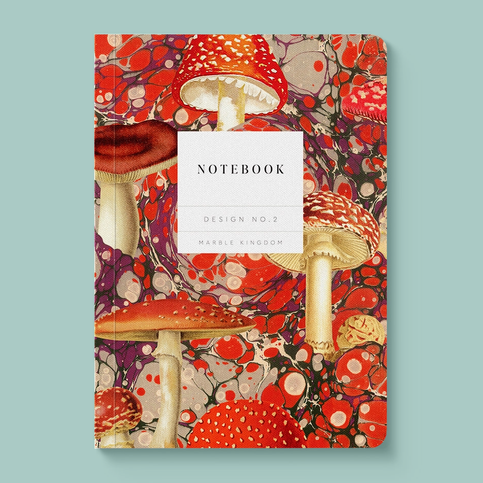 A notebook with a vibrant, detailed cover illustration of red and white mushrooms over a red, purple, and black marbled pattern. The center of the cover features a white rectangular label with the text 'NOTEBOOK', 'DESIGN NO.2'