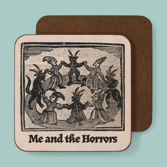 A square coaster with rounded corners featuring a vintage black-and-cream woodcut illustration of whimsical monsters and the text 'Me and the Horrors,' shown in front of a coaster with a brown back on a light aqua background.