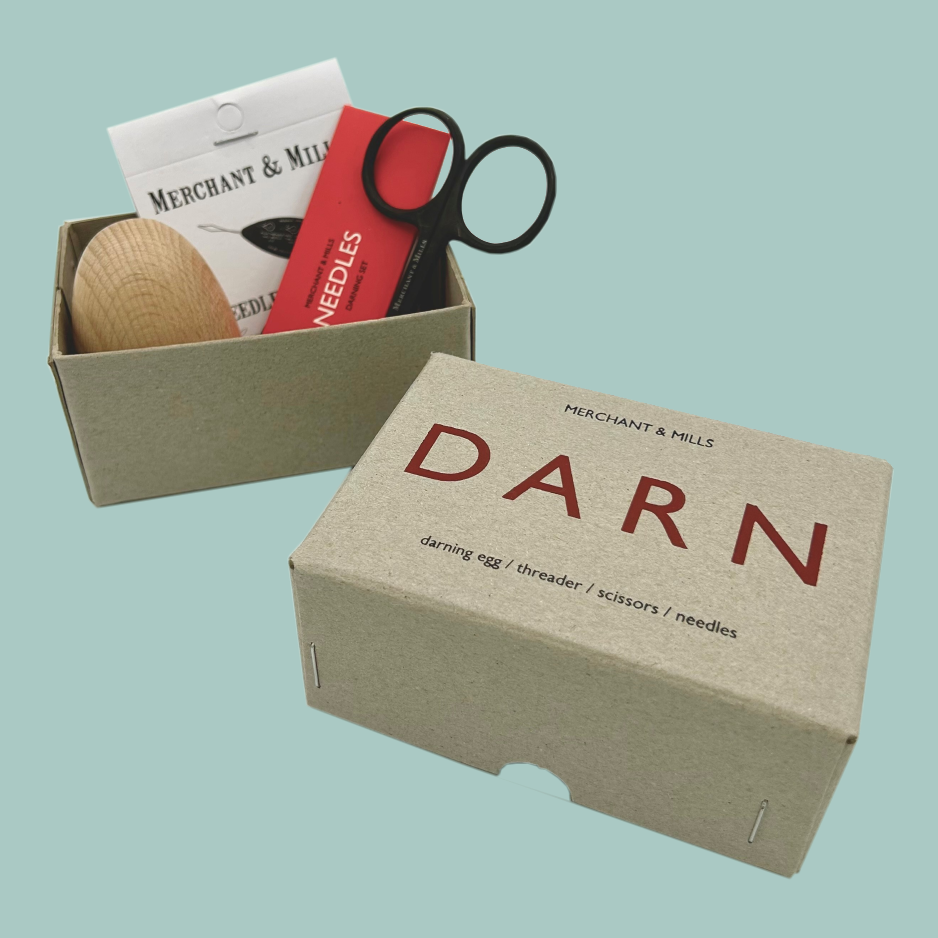 Box labeled 'DARN' containing darning tools on a light blue background