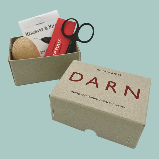 Box labeled 'DARN' containing darning tools on a light blue background