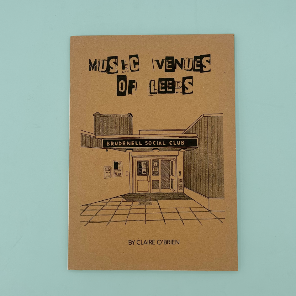 An A5 zine titled "Music Venues of Leeds" by Claire O'Brien, featuring a brown kraft-paper cover with black illustrated building artwork and text, photographed against a light blue background.