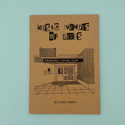 An A5 zine titled "Music Venues of Leeds" by Claire O'Brien, featuring a brown kraft-paper cover with black illustrated building artwork and text, photographed against a light blue background.