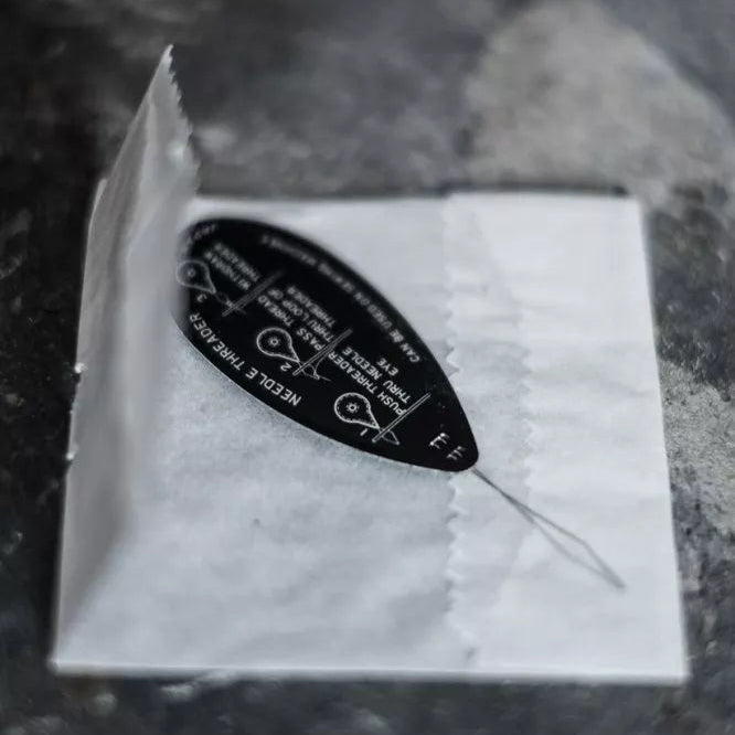 Needle threader with packaging on a dark surface
