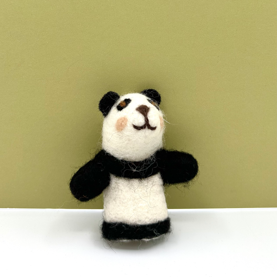 A small felted wool panda finger puppet toy standing upright on a white surface against a solid olive green background.