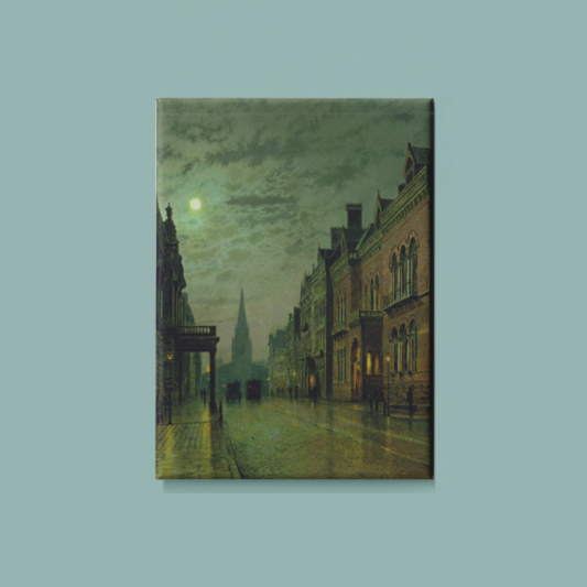 A rectangular magnet of a painting of a city street at night on a light blue background