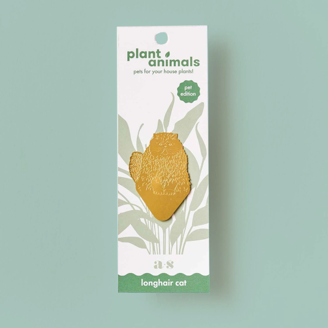 Cat-shaped brass decoration with a pointed base, on a white backing card. 