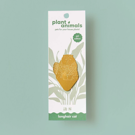 Cat-shaped brass decoration with a pointed base, on a white backing card. 