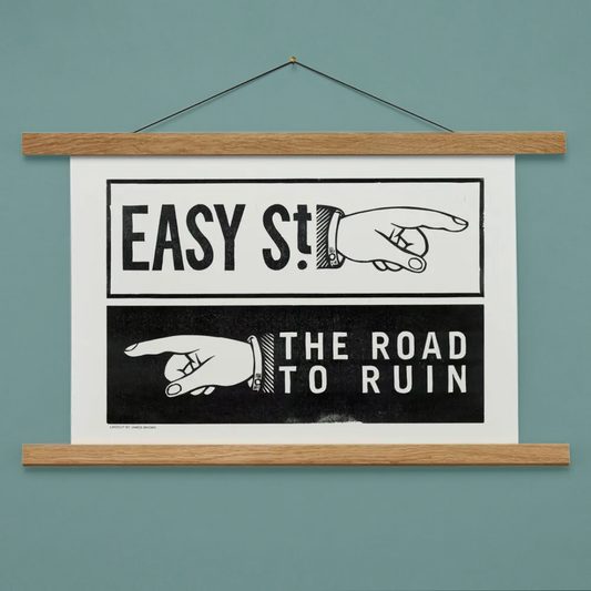 Framed poster with text 'EASY ST!' and 'THE ROAD TO RUIN' on a teal wall.