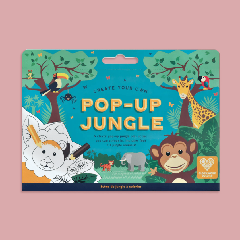 A children's pop-up jungle colouring set, featuring colorful cartoon animal illustrations including a giraffe, monkey, elephant, toucan, and lion on a blue jungle-themed cover, shown against a solid pink background.