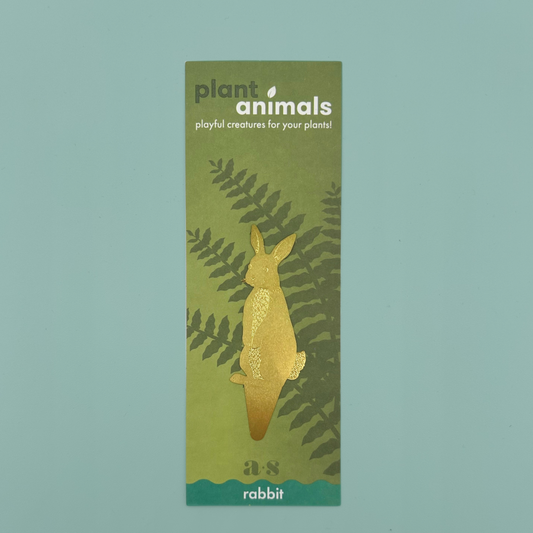 Brass rabbit-shaped decoration with a pointed base, on a green backing card.