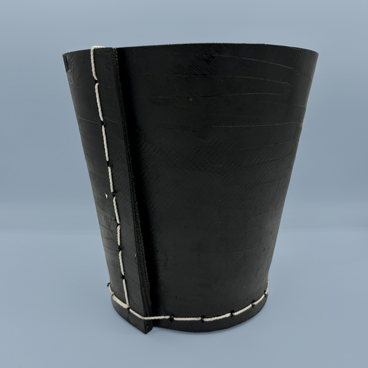 Black rubber plant pot with white stitching on a blue background