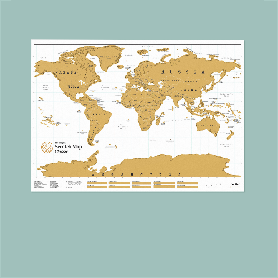 A Scratch Map Classic world map poster shown flat against a solid sage green background. The map features gold-colored continents with black labels and grid lines on a white background, with the Scratch Map logo in the lower-left corner.