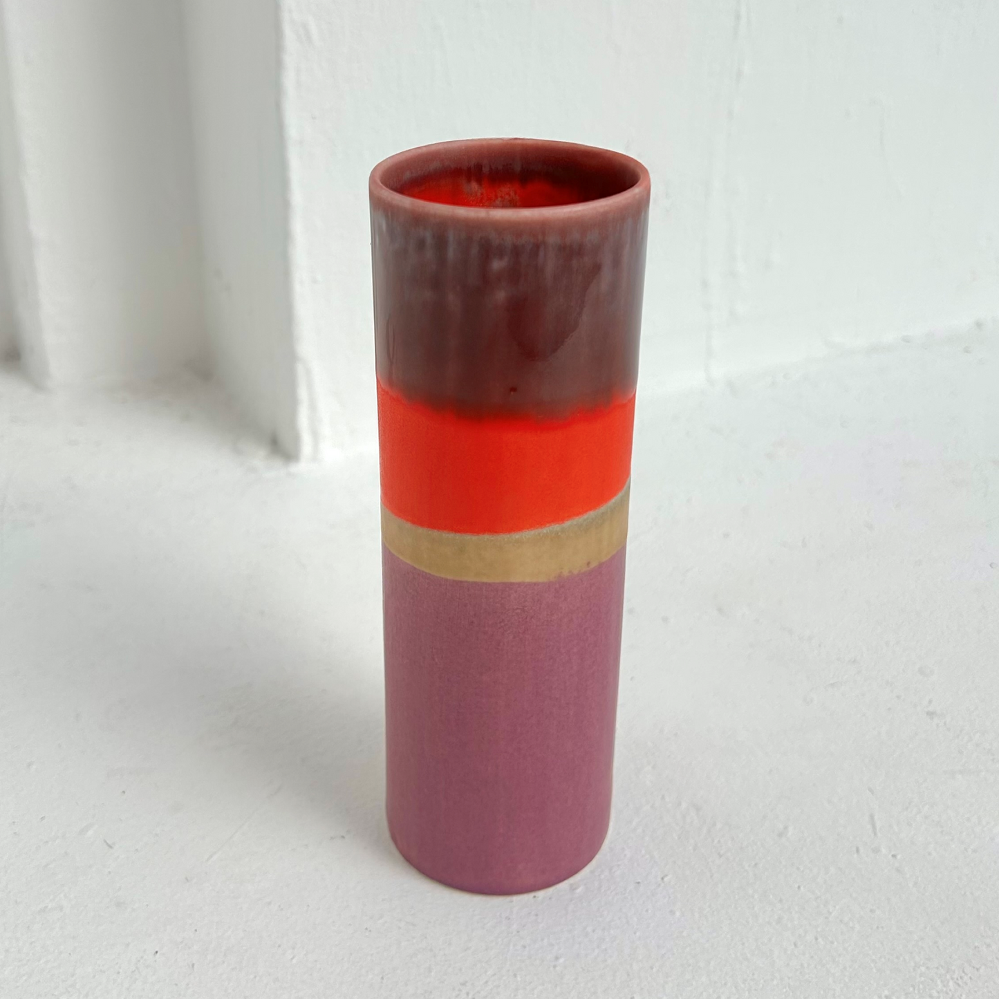 Cylindrical vase with layered colors on a white background