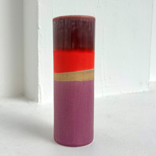 Cylindrical vase with purple, red, and gold stripes on a white background.