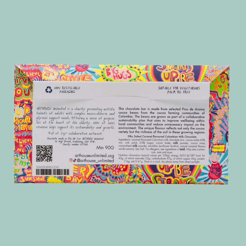 A colorful  product box with a white back label, photographed against a solid pale green background. The box features a highly vibrant, multicolored abstract pattern on the front and a white informational panel on the back with text, QR code, and logos.