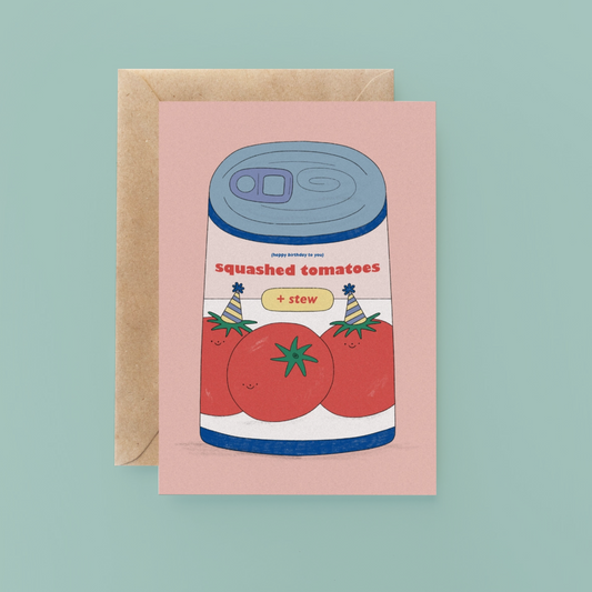 Greeting card with a can of 'Squashed Tomatoes + Stew' design on a pink background, with a brown envelope.