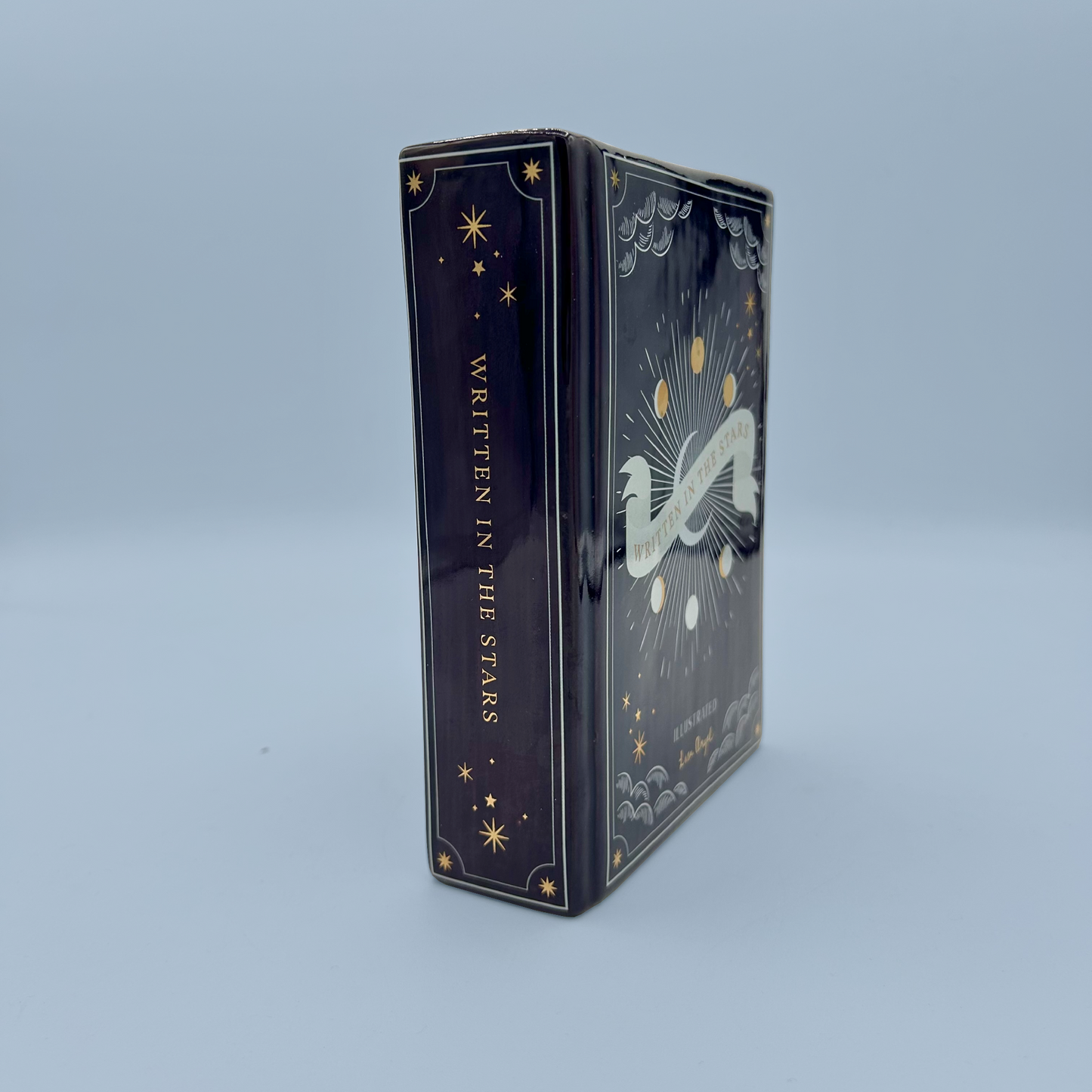 Decorative book vase with celestial design and 'Written in the Stars' text on a light blue background