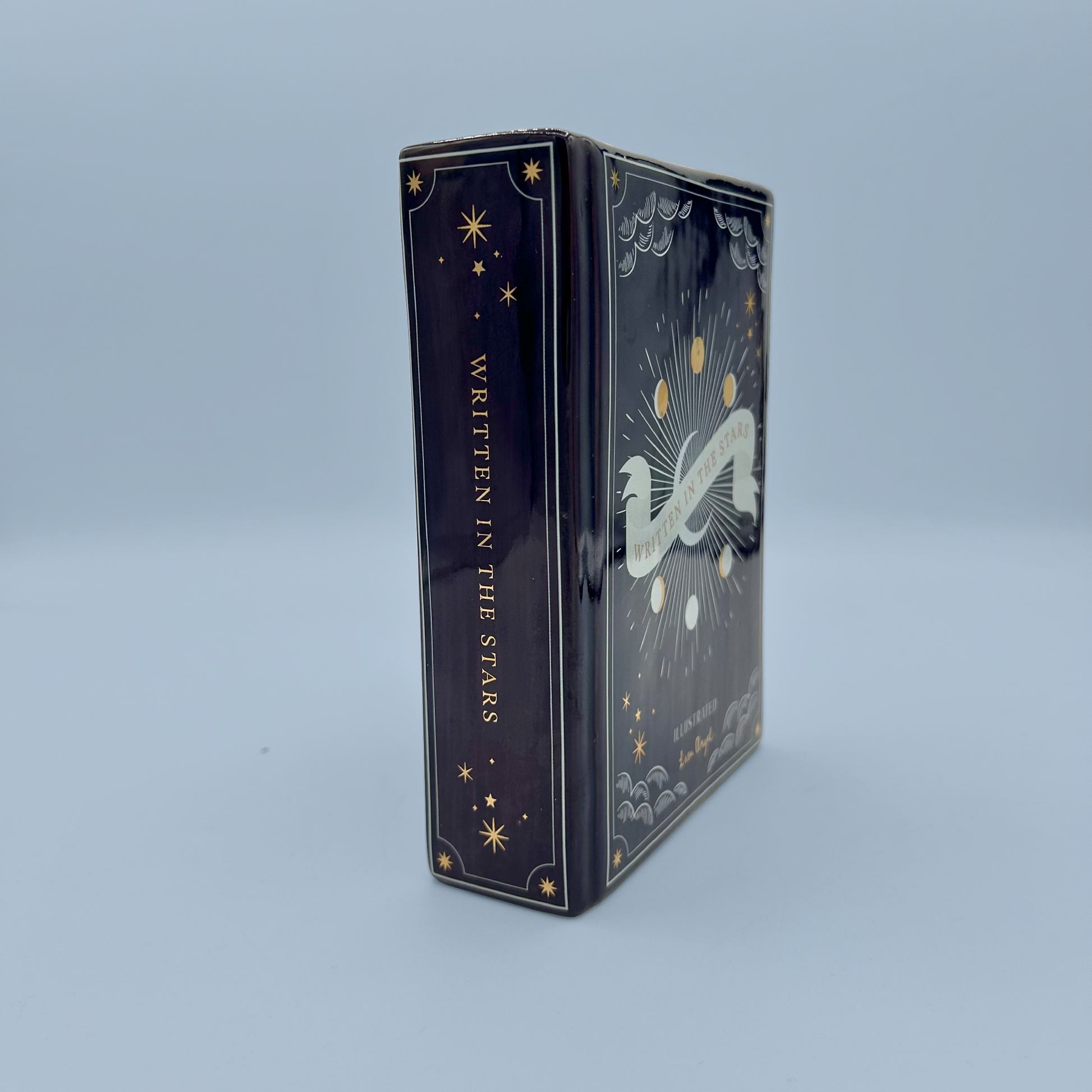 Decorative book vase with celestial design and 'Written in the Stars' text on a light blue background