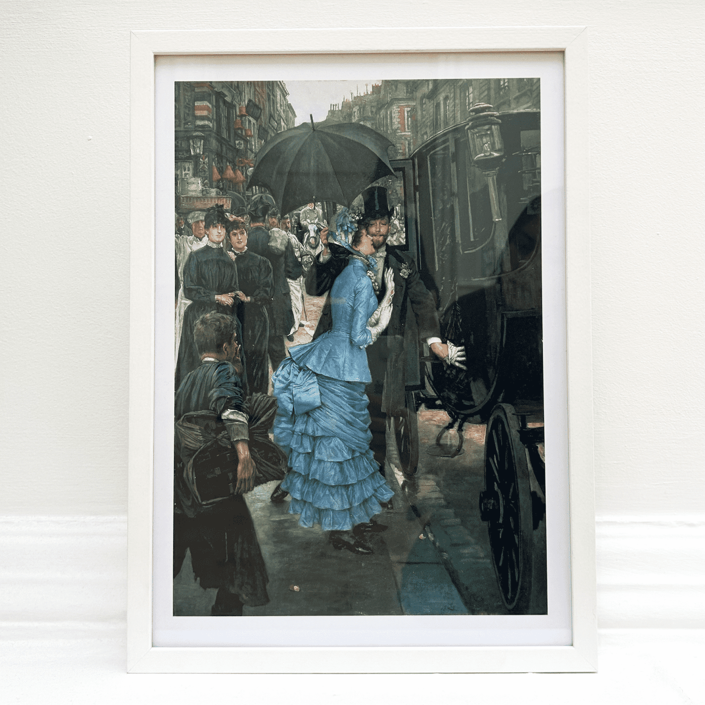 Framed artwork of a woman in a blue dress with an umbrella on a city street.