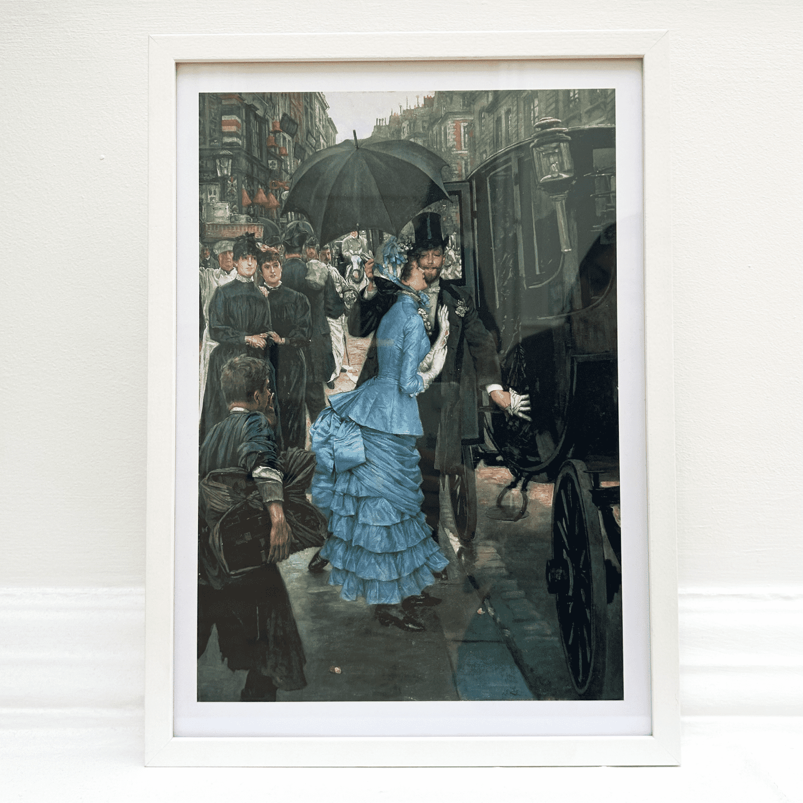 Framed artwork of a woman in a blue dress with an umbrella on a city street.