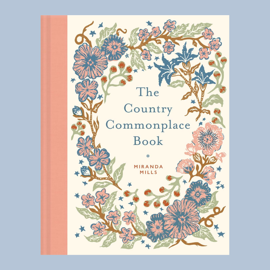 The Country Commonplace Book by Miranda Mills, featuring a cream-colored cover with a detailed botanical border of pink, blue, and green flowers, set against a solid light blue background.