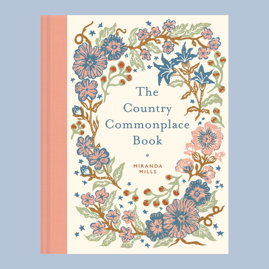 The Country Commonplace Book by Miranda Mills, featuring a cream-colored cover with a detailed botanical border of pink, blue, and green flowers, set against a solid light blue background.
