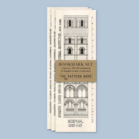 A set of three vintage-style bookmarks fanned out against a solid light blue background. The bookmarks are cream-colored with black architectural line drawings of Norman Gothic cathedrals and a central tan belly band reading 'BOOKMARK SET' and 'THE PATTERN BOOK'.