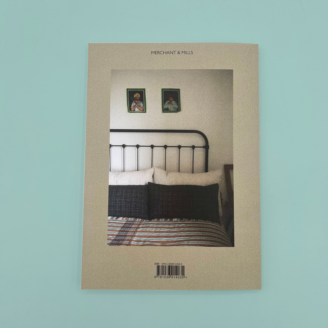 Back cover of a grey book, with a photograph of a bed on it. 