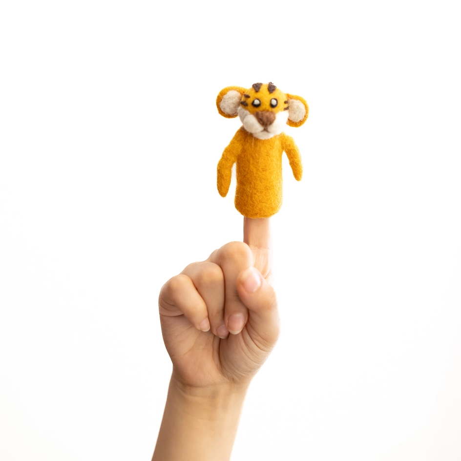 A small felt animal finger puppet, shaped like a tiger in orange and brown, being held on a child's index finger against a plain white background.