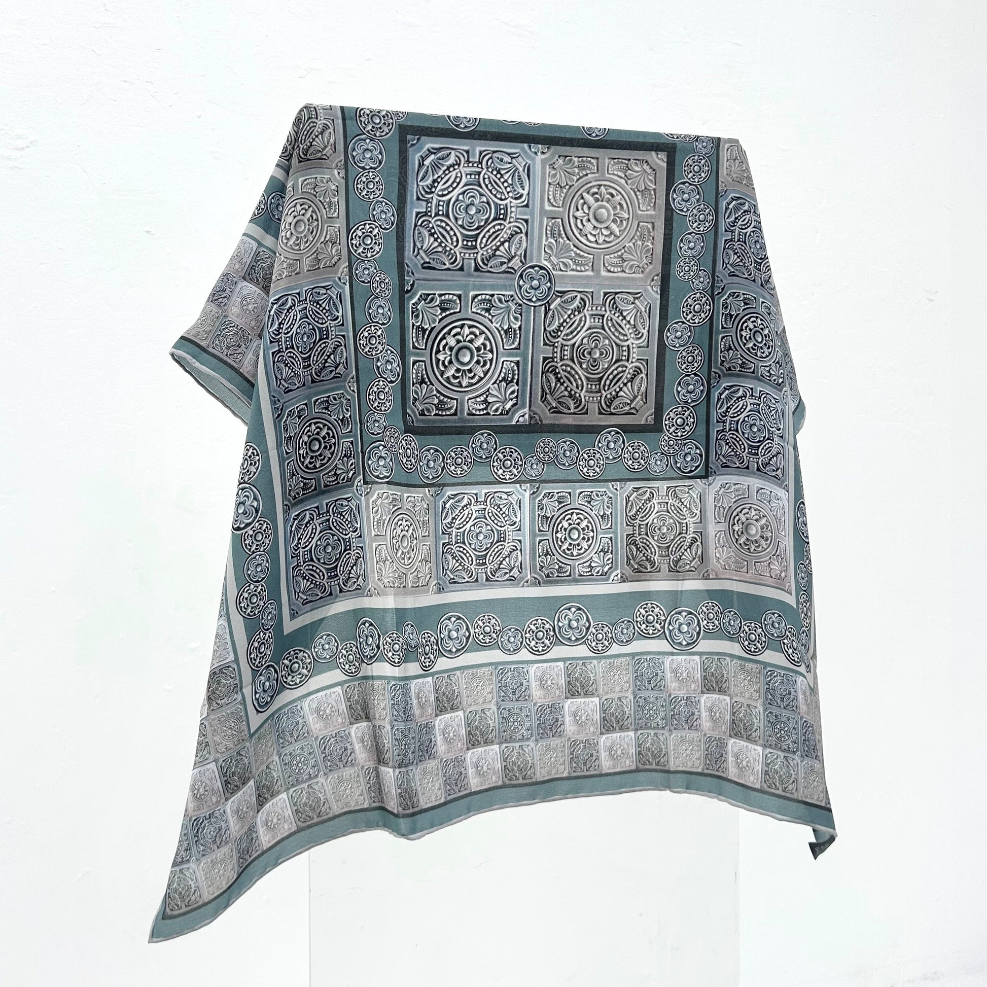 A grey patterned scarf on a white background. 